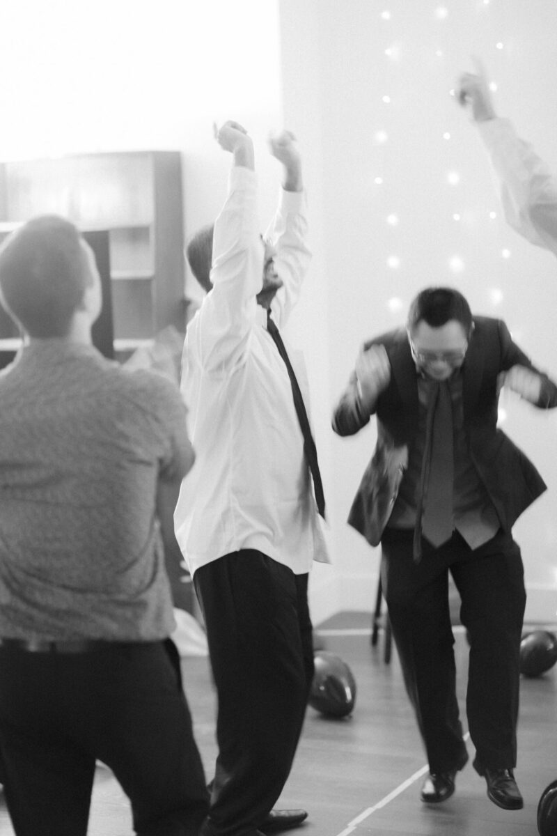 [ID: a black and white photo of people dancing in suits.]